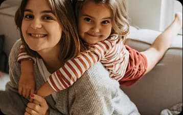 Jeune femme portant une enfant souriante